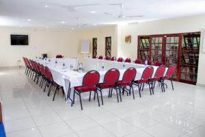 a long table with red chairs in a room at Matilinda Lodge in Bulawayo