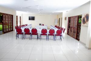 uma sala de conferências com uma mesa longa e cadeiras vermelhas em Matilinda Lodge em Bulawayo