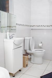 een witte badkamer met een toilet en een wastafel bij Matilinda Lodge in Bulawayo