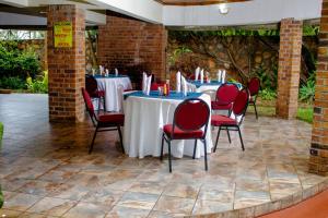 a group of tables with red chairs in a room at Matilinda Lodge in Bulawayo