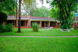 a building with tables and chairs in a yard at Matilinda Lodge in Bulawayo