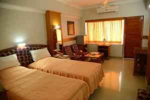 a hotel room with two beds and a living room at Hotel City Tower in Coimbatore