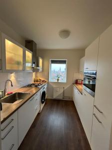 uma cozinha com armários brancos, um lavatório e uma janela em Apartment with city skyline em Leeuwarden