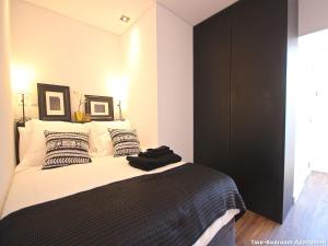 Schlafzimmer mit einem Bett mit schwarzen und weißen Kissen in der Unterkunft Akicity Liberdade Star in Lissabon