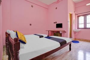 two beds in a room with pink walls at OYO Hotel SS Residency in Punalūr