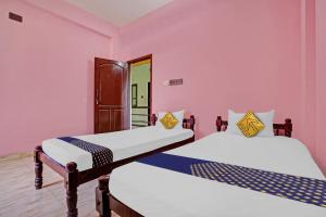 two beds in a room with pink walls at OYO Hotel SS Residency in Punalūr