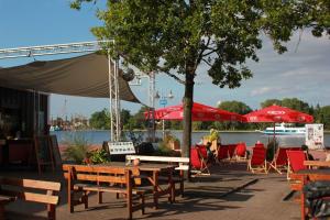 grupa stołów i krzeseł z czerwonymi parasolami w obiekcie Circus Fantasia w mieście Rostock