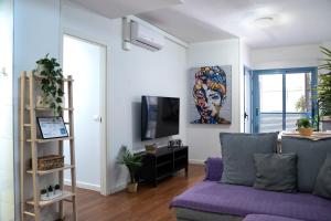 a living room with a purple couch and a tv at Apartamento Cerca de la playa in Benidorm