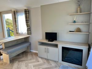 ein Wohnzimmer mit einem TV und einem Schreibtisch mit einem TV in der Unterkunft Perranporth Golf Club Self-Catering Holiday Accommodation in Perranporth + 24 Fotos