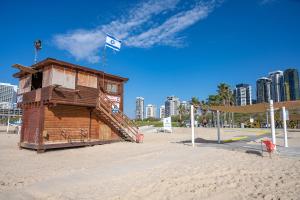 a small wooden building on a beach with a city at Sweet Love - דירה מהממת על הים עם נוף in Bat Yam