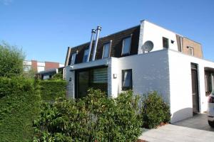 ein weißes und schwarzes Haus mit einem davor geparkt in der Unterkunft Lamsoor 9A* in Nieuwvliet