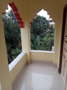 an empty room with two large windows in a house at Nidhivan Residency in Navadwīp