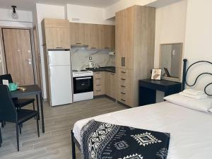 a bedroom with a bed and a kitchen with a desk at Downtown New Studio PM1 (ΠΜ1) in Larisa