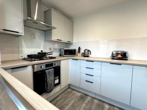 a kitchen with white cabinets and a stove top oven at Wallis House by Blue Skies Stays in Stockton-on-Tees