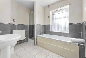 łazienka z wanną, umywalką i oknem w obiekcie Ensuite Room in Cardiff City Centre w Cardiff