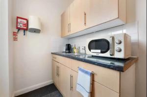 a small kitchen with a microwave and a sink at Ensuite Room in Cardiff City Centre in Cardiff