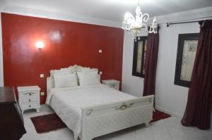 a bedroom with a white bed with a red wall at Riad Baddi in Salé