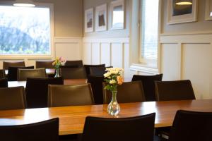 uma sala cheia de mesas e cadeiras com um vaso de flores em Hestaland Guesthouse Horse Farm Stay em Staðarhús