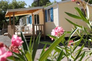 ein winziges Haus mit einer Veranda und rosa Blumen in der Unterkunft Camping Lou Cantaire in Fayence