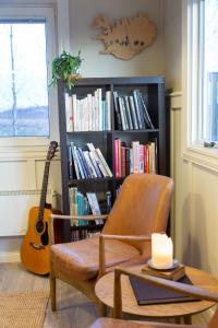 una sala de estar con una silla y una estantería con libros en Hestaland Guesthouse Horse Farm Stay, en Staðarhús