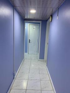a hallway with blue walls and a white door at Bright Rooms in Dubai