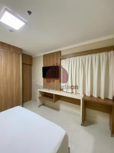 a bedroom with a bed and a desk with a television at Piazza diRoma com acesso ao Acqua Park in Caldas Novas