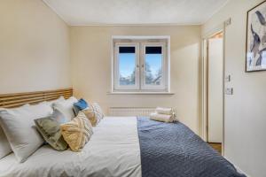 a bedroom with a bed with pillows and a window at Executive 4 Bedroom Town House in Canada Water FREE WIFI & PARKING by City Stay Aparts London in London