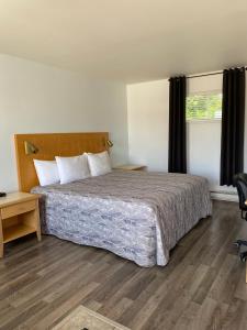 Un dormitorio con una cama grande y una ventana en Motel Centre-Ville, en Montmagny
