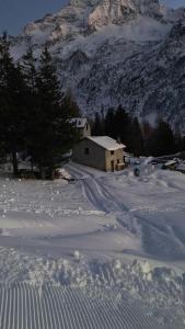 una casa coperta di neve di fronte a una montagna di Chalet Baita Aria a Ponte di Legno
