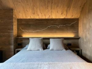 een slaapkamer met een bed met 2 kussens bij Chalet Baita Aria in Ponte di Legno