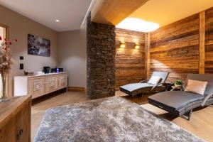 a living room with two chairs and a stone wall at CGH Résidences & Spas Alpaga in La Toussuire