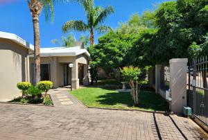 a house with palm trees and a driveway at Green Kalahari Guesthouse in Upington