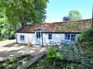 a small white cottage with a garden in front of it at 1 Bed in Cley NCC04 in Cley next the Sea