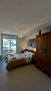 a bedroom with a bed and a large window at Résidence Les Balcons du Pic d'Anie in Arette