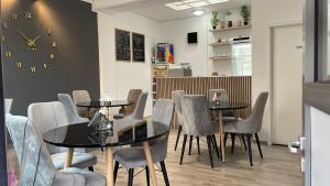 a dining room with two tables and chairs and a clock at Riverside Airport Hotel in Kelsterbach