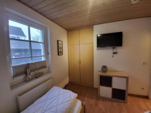a bedroom with a bed and a tv on the wall at Ferienwohnung Kajüte 19 in Greetsiel