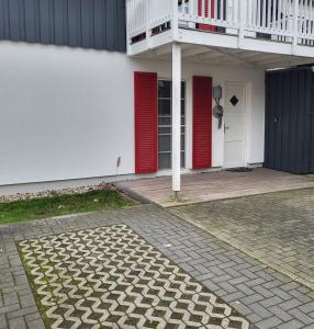 ein Gebäude mit roten Türen und einem Balkon in der Unterkunft Ferienwohnung Kajüte 19 in Greetsiel