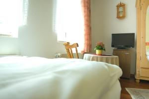 a bedroom with a white bed and a television at Pension Am Alten Markt in Halle an der Saale