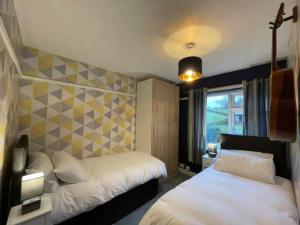 Habitación de hotel con 2 camas y ventana en 3BR Pet and Bike Friendly Cosy Haven Pass the Keys en Glossop