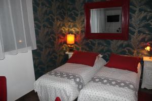 a bedroom with two beds with red pillows and a mirror at PARIS de FLORE Stane in Malakoff