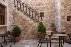 a patio with chairs and tables and a stone wall at Μikri Arktos Boutique Hotel in Dhimitsana