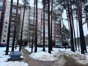 un edificio de apartamentos con árboles y nieve delante de él en Real appartments, en Visaginas