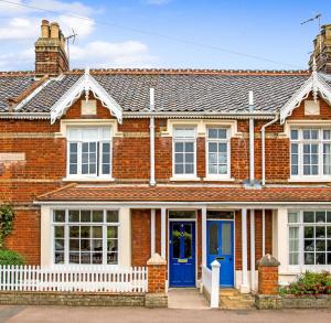 uma casa de tijolos vermelhos com portas azuis em Eastholme, style and luxury in Southwold, Suffolk em Southwold