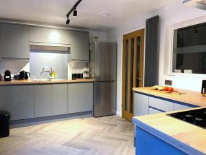 a kitchen with gray cabinets and a stainless steel refrigerator at Bard's Nest Scholars Cottage, Central Stratford, 5 mins walk to RSC in Stratford-upon-Avon