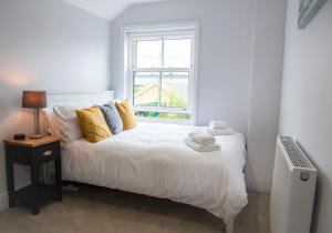 um quarto com uma cama branca e uma janela em Eastholme, style and luxury in Southwold, Suffolk em Southwold