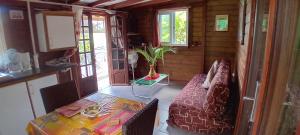 ein Wohnzimmer mit einem Tisch und einem Sofa sowie einem Tisch und Stühlen in der Unterkunft La kaz créole 2 in Bouillante