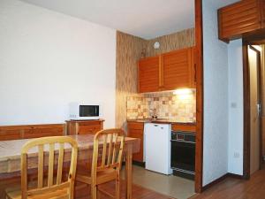 uma cozinha com uma mesa e cadeiras e um frigorífico branco em Appartement Les Orres, 1 pièce, 4 personnes - FR-1-322-122 em Les Orres