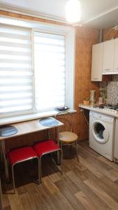 een keuken met een tafel en stoelen en een wasmachine bij Квартира у метро Спортивная in Charkov
