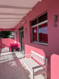 ein rosafarbenes Haus mit einer Bank auf einer Veranda in der Unterkunft Terrasse des Manguiers : logement indépendant in Pointe-Noire
