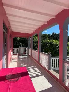eine rosa Veranda mit einem roten Teppich in der Unterkunft Terrasse des Manguiers : logement indépendant in Pointe-Noire